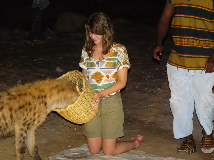a woman in a safari shirt pets a hyena