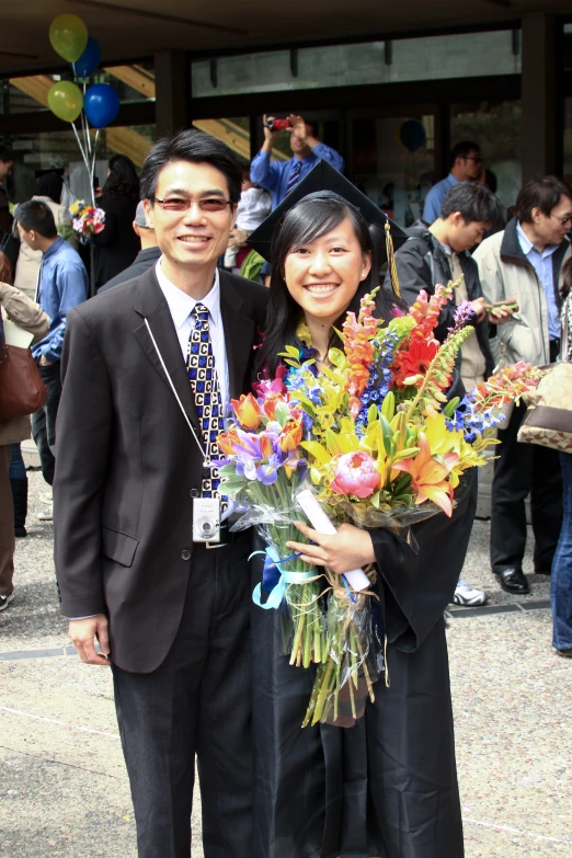 a couple is posing for a picture outside during the graduation ceremony