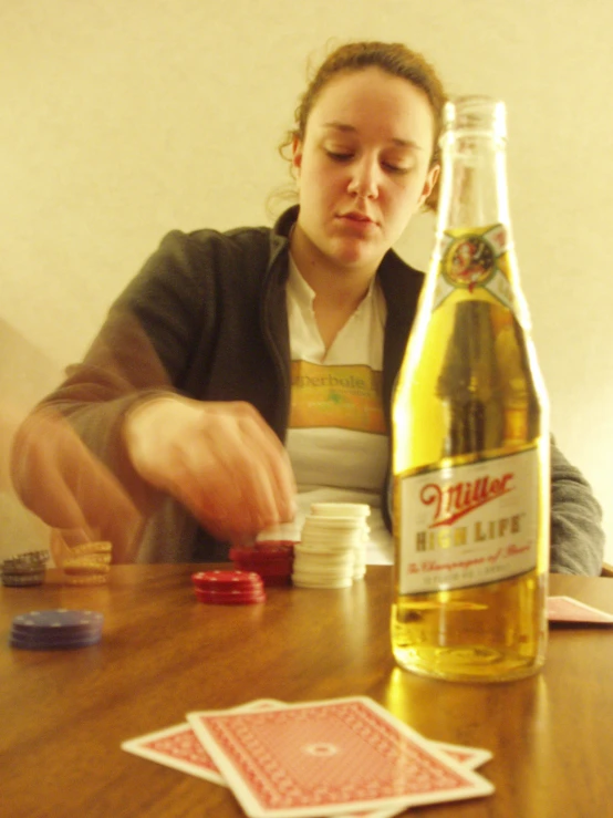 a woman is playing cards and a bottle of beer