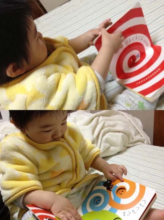 a baby is reading a book while his mom looks on