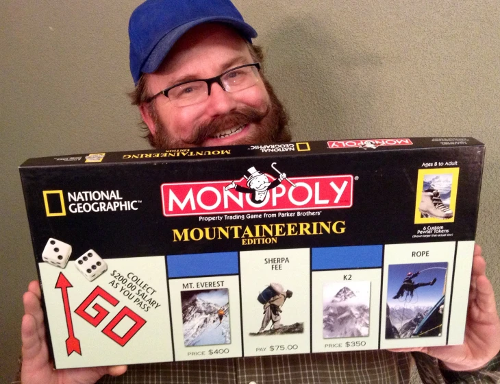 a man holding up a board game box with mountaineering in it