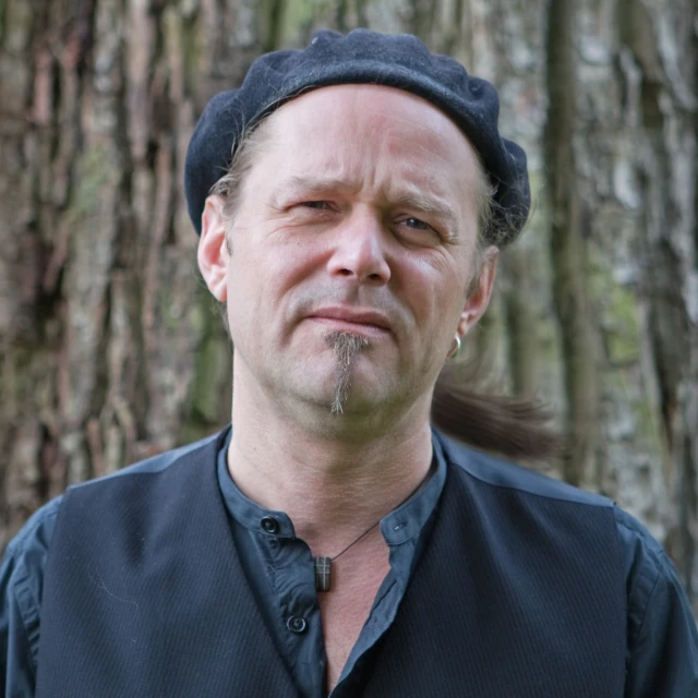 a man with very hairy facial is next to the tree