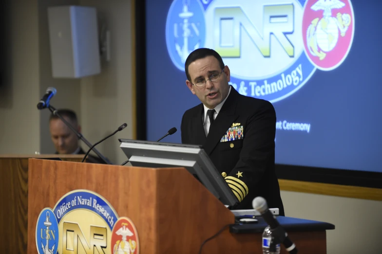 a man stands in front of a podium at a meeting