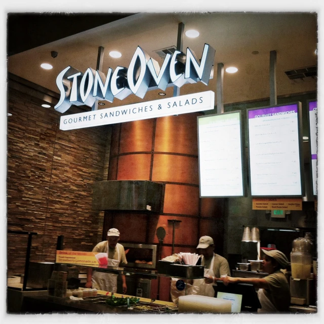 two men preparing food in front of a sign