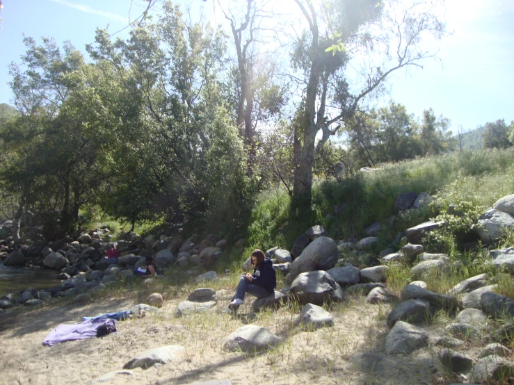 people sitting and resting on large rocks under trees