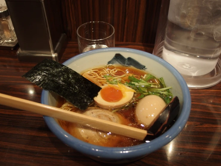 a bowl full of ramen and soup with chopsticks on the side