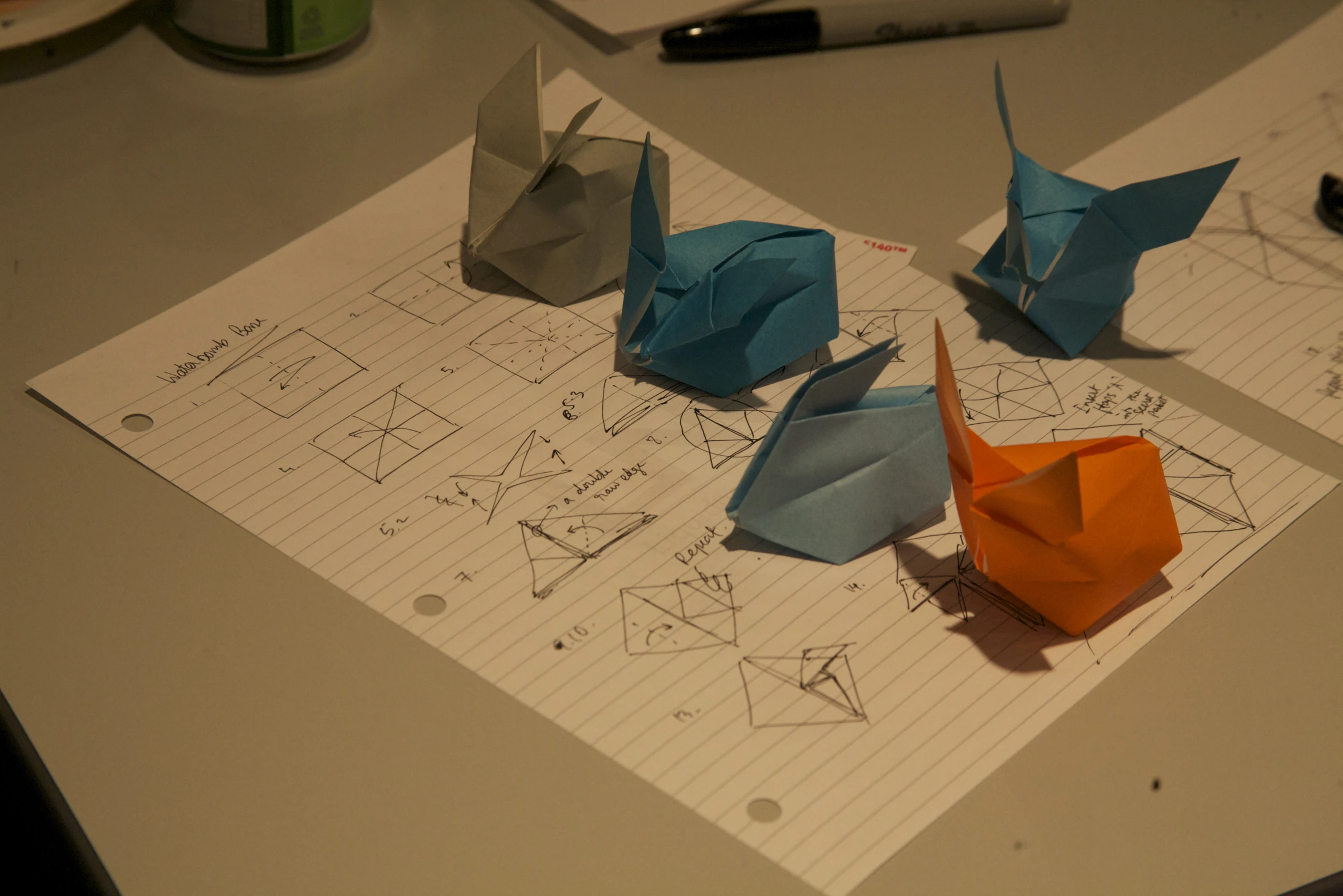 three origami birds sitting on paper that is being folded