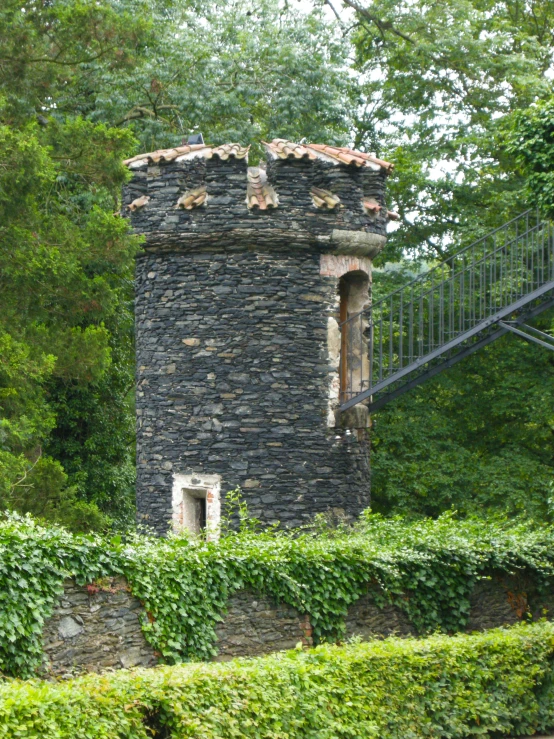 a brick tower sitting between two tall hedges