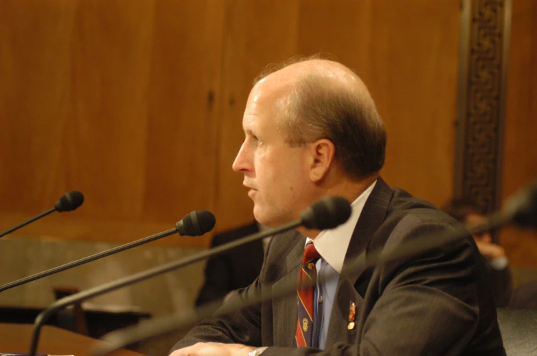 a man sitting at a microphone looking off into the distance