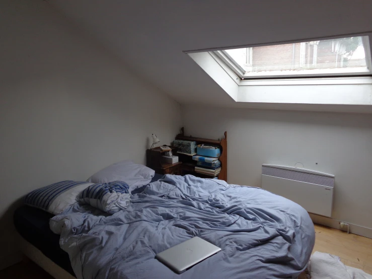 a bed in an attic with a laptop on it