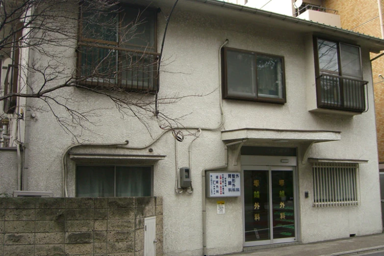 there is a small white building with an iron railing and trees outside it