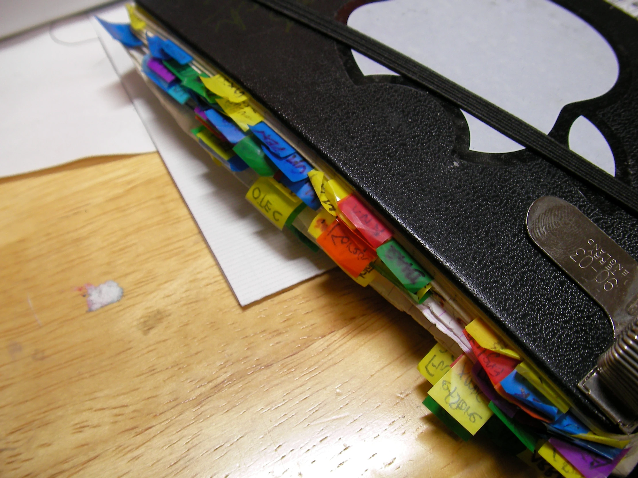 many colorful markers stuck in a folder on a wooden table