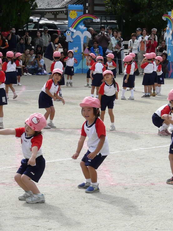 a group of young children with pink hats play in the sand