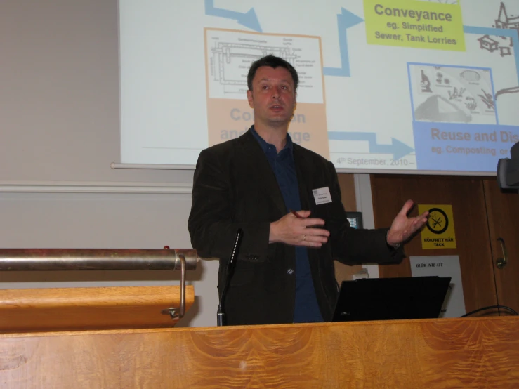 a man standing at a podium in front of a projector