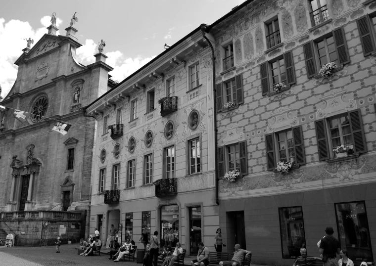 people are sitting on benches and talking outside of an old building