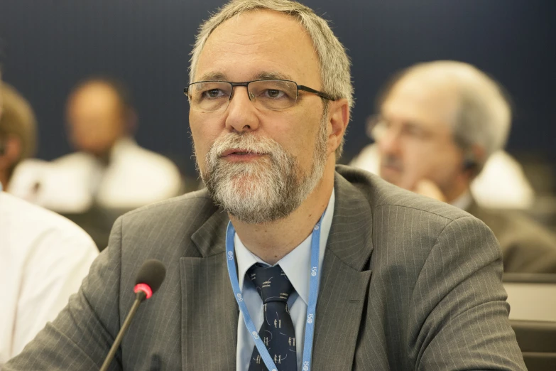 a man sitting at a table with two men in the background