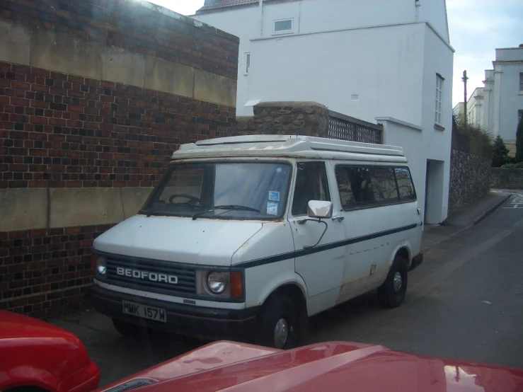 an old, small white van parked next to a brick building