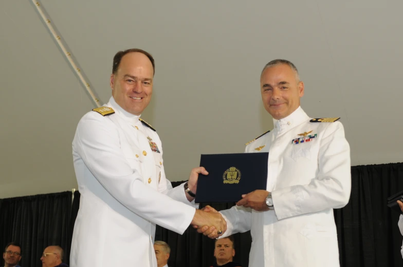 two men are shaking hands at an award ceremony