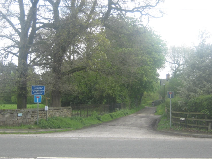 an empty road lined with stone fences next to trees