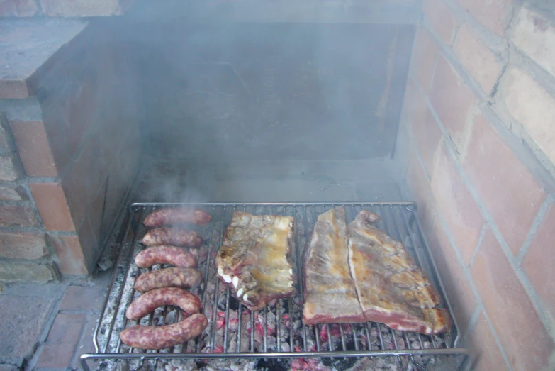there are various meats and sausages being cooked on the grill