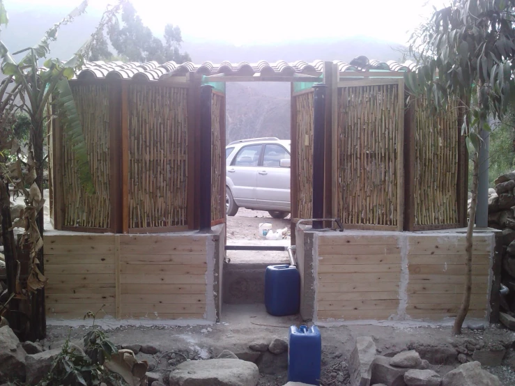 a white car is parked behind a building with bamboo walls