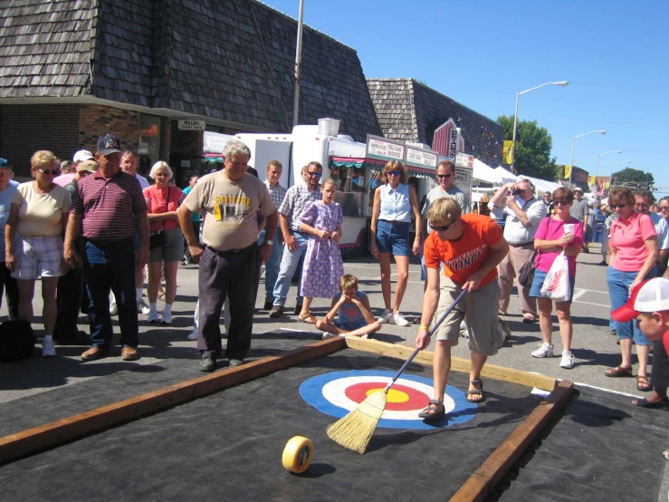 a group of people watching as a man hits a ball with a tee