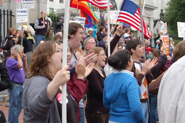 a large crowd has stopped at the corner of a street