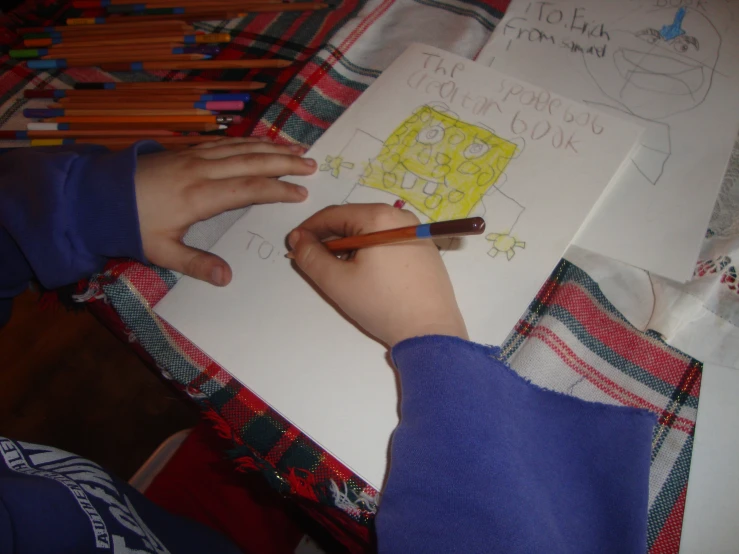 a child holding a pencil and drawing soing