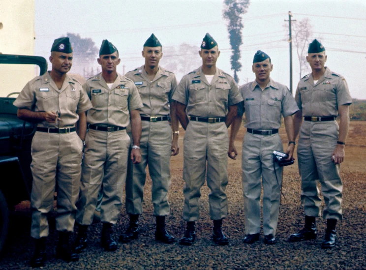 a group of men in uniform next to a vehicle