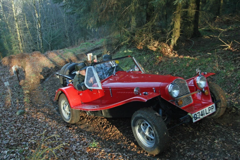 a red car is sitting in the woods