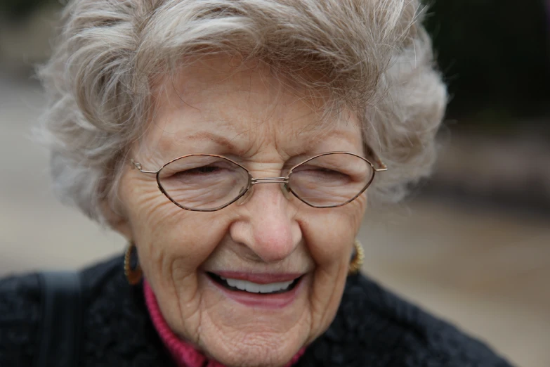 a woman wearing glasses laughing while standing in the street