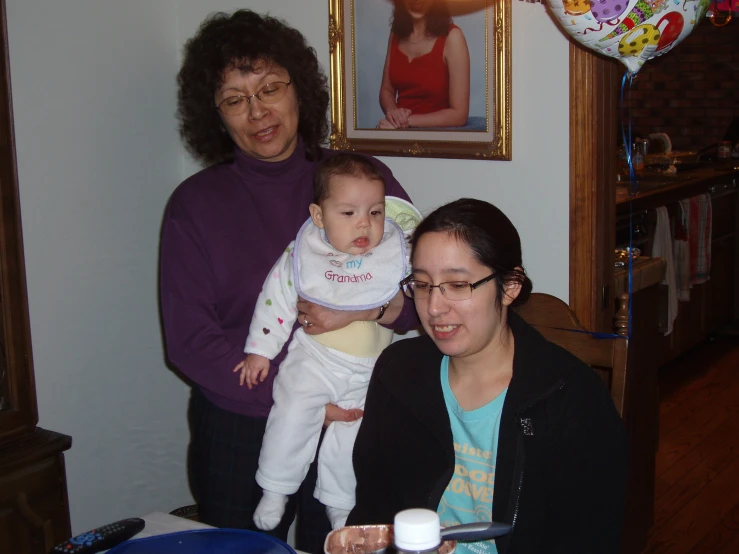 a woman holding up a baby, sitting in front of a man