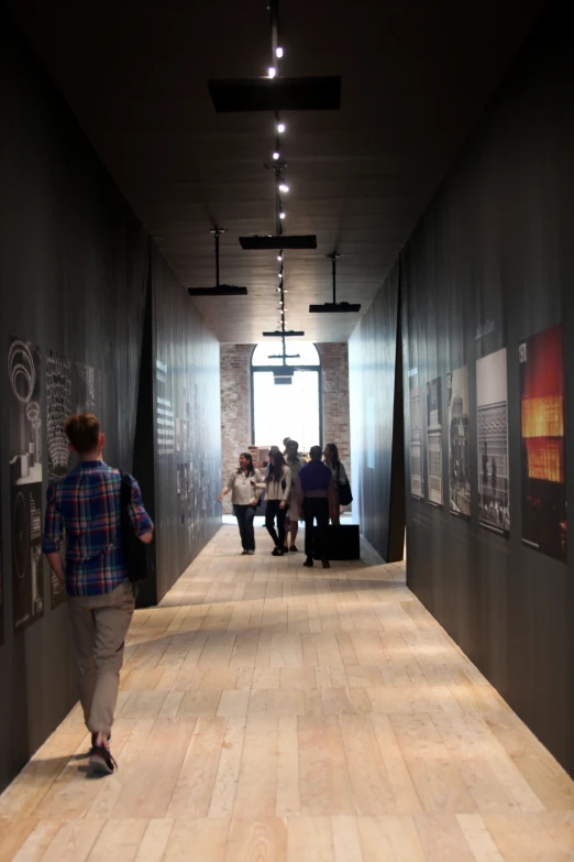 several people walking down a dark hallway at a museum