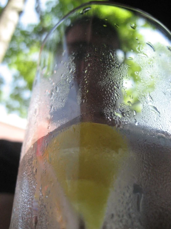 a glass filled with liquid and lemon on top of a table