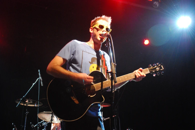 a man that is standing next to a guitar