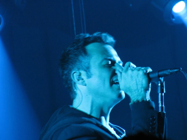 the man is singing into the microphone on stage