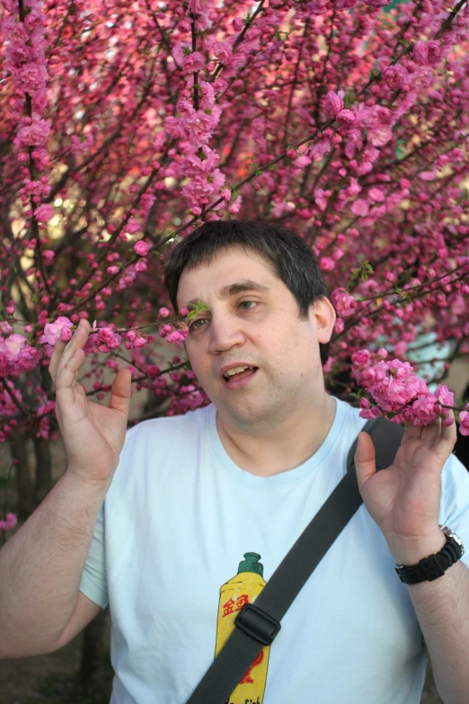 man standing next to a flowering tree with fruit on it