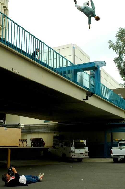 a person on the ground next to cars and under a bridge