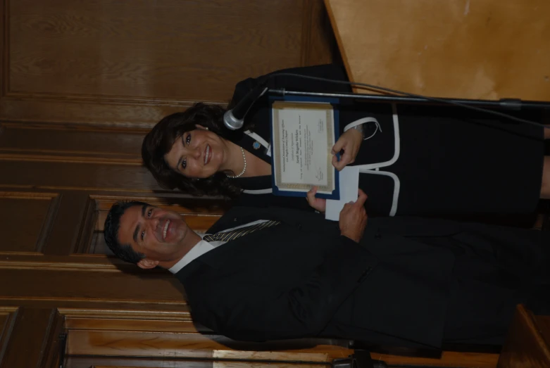 a man standing next to a woman who is holding a plaque