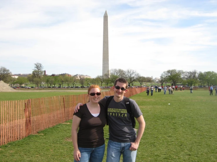 a man and woman are posing in front of the washington monument