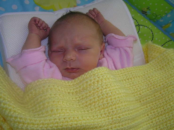 a baby sleeping under a blanket in a bed