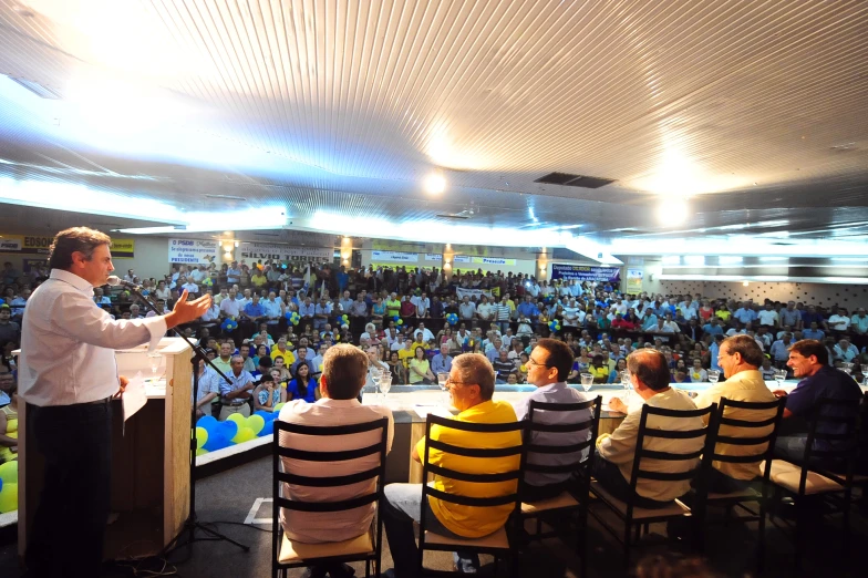 a crowd of people is sitting in chairs with a speaker