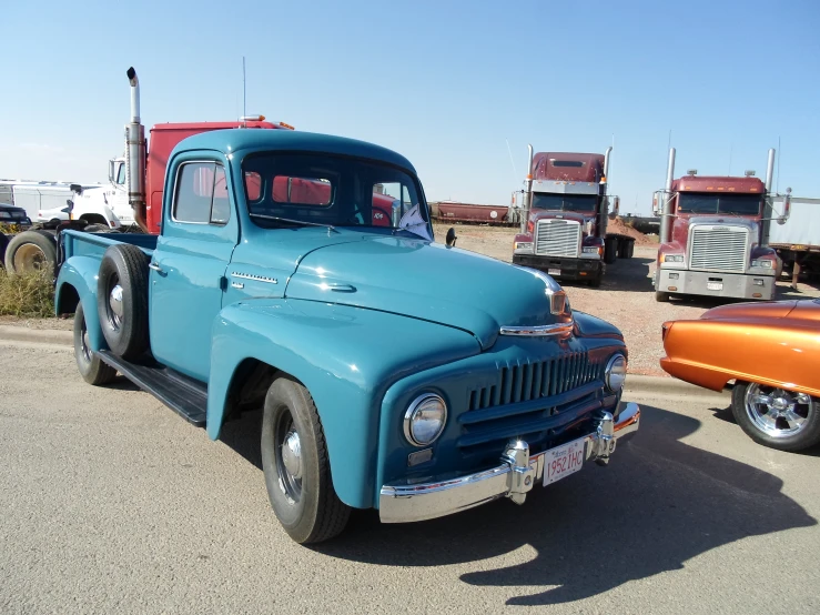 an old blue truck parked next to other cars