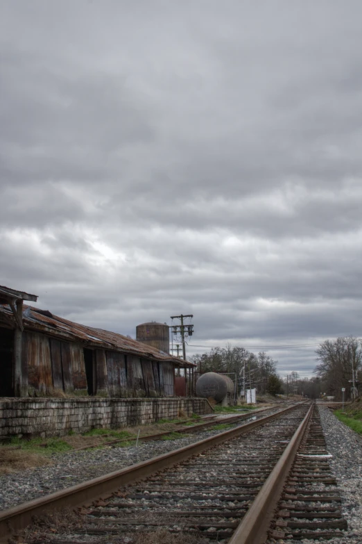 a train track with buildings and water towers in the background