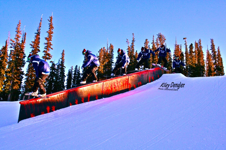 three snow boarders riding down the side of a wall