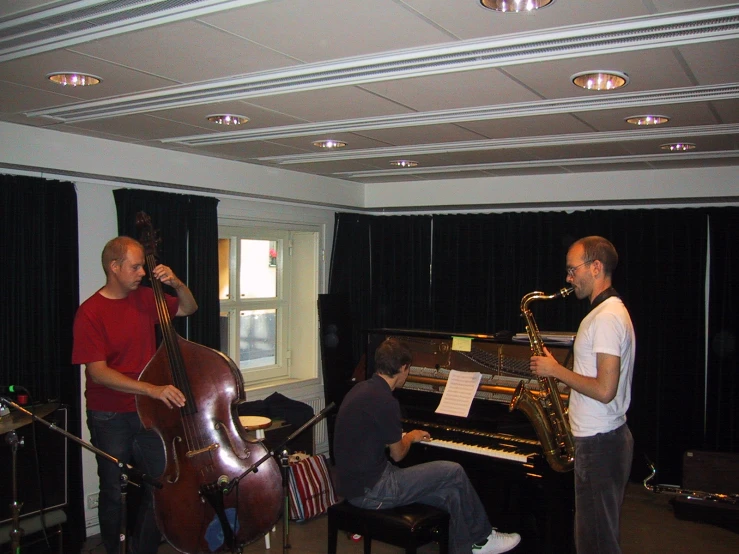 two men in a recording studio while one plays the piano