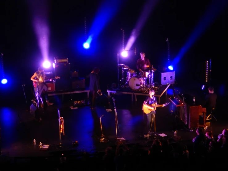 band performing on stage at night on a purple light