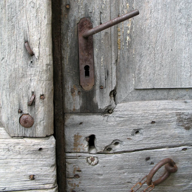 a door has the handles missing and a piece of rusty metal is visible
