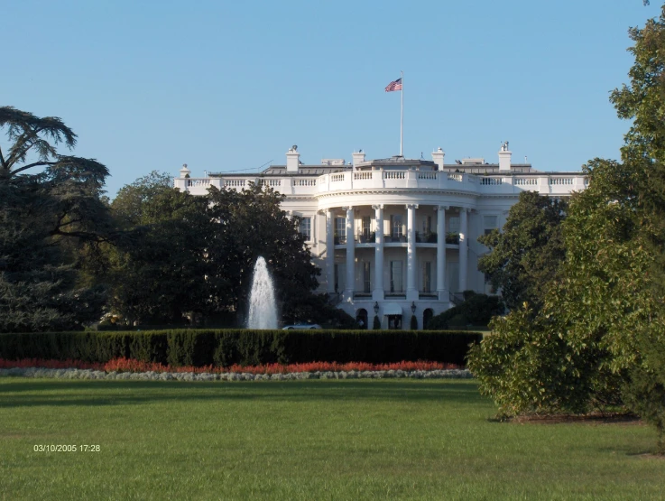 the white house with gardens in front on a sunny day