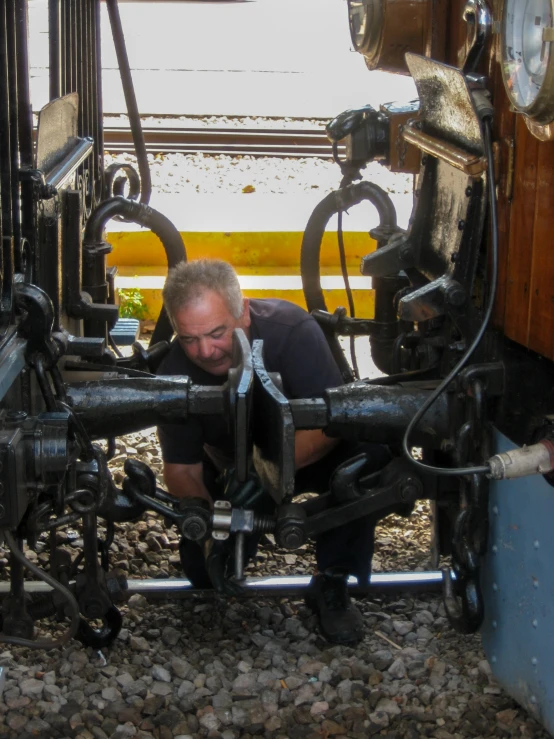 man crouched down and touching large metal pipes